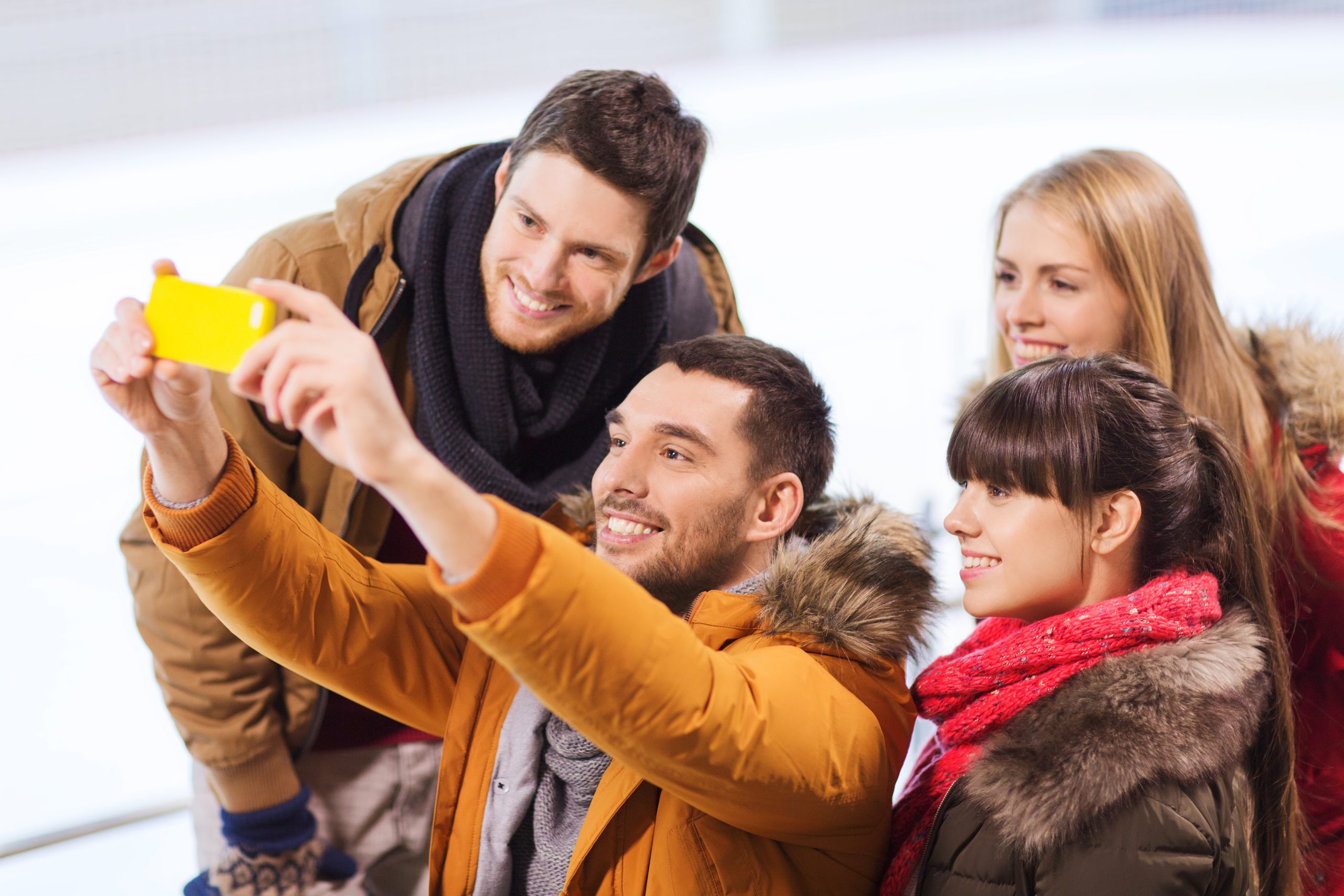 people, friendship, technology and leisure concept - happy friends taking selfie with smartphone on skating rink